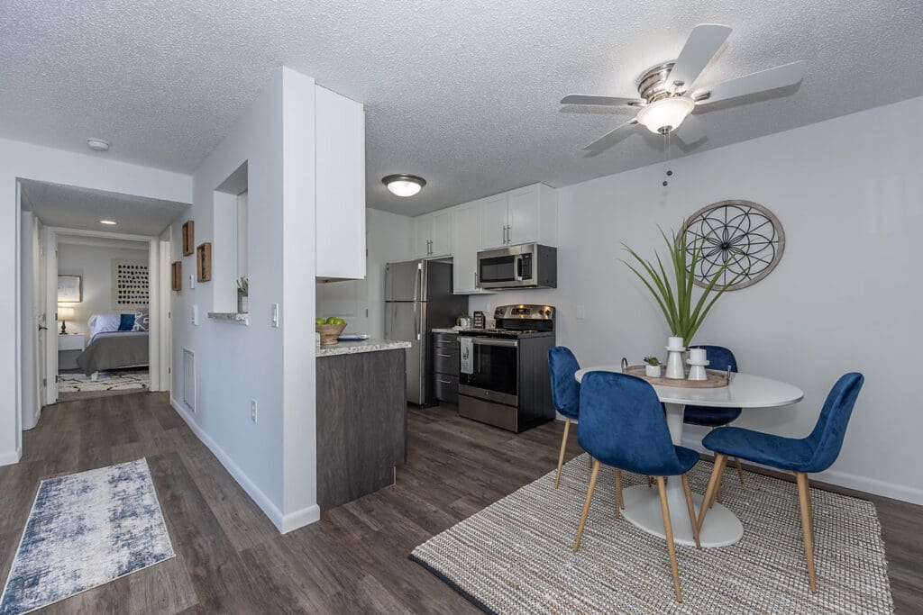 Stylishly decorated kitchen and dining area in a Windsor Place apartment, Beavercreek, Ohio, featuring blue chairs and contemporary design.
